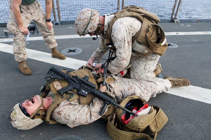 A Marine assigned to Combat Logistics Battalion 26, 26th Marine Expeditionary Unit, treats a simulated casualty as part of a combat life saver exercise aboard the amphibious dock landing ship USS Oak Hill.