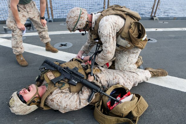 A Marine assigned to Combat Logistics Battalion 26, 26th Marine Expeditionary Unit, treats a simulated casualty as part of a combat life saver exercise aboard the amphibious dock landing ship USS Oak Hill.