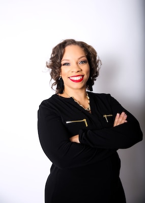 Woman dressed in black standing in front of a white background.