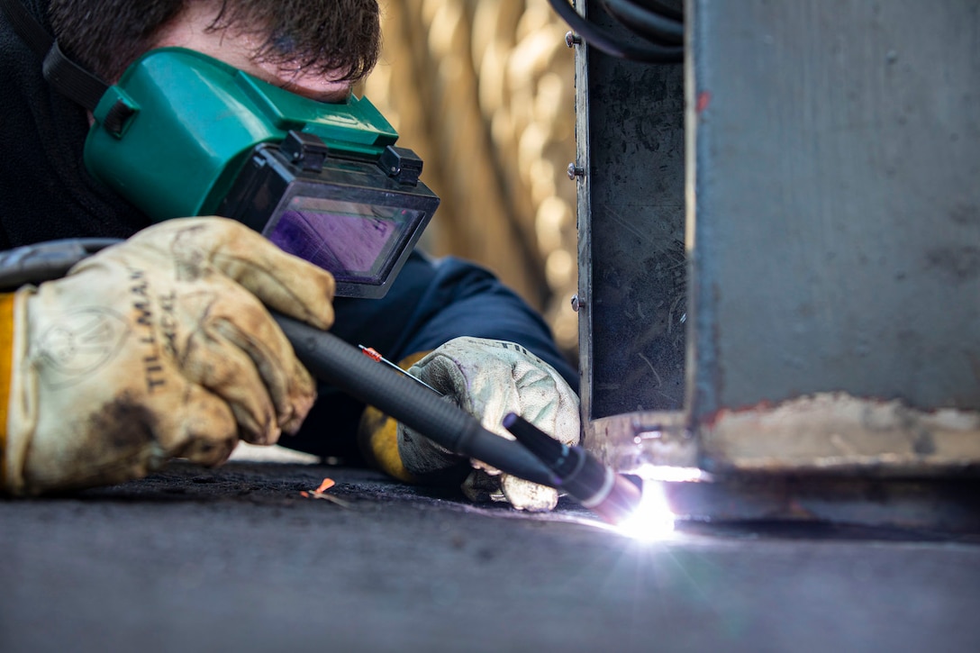 A sailor wears protective goggles while welding.