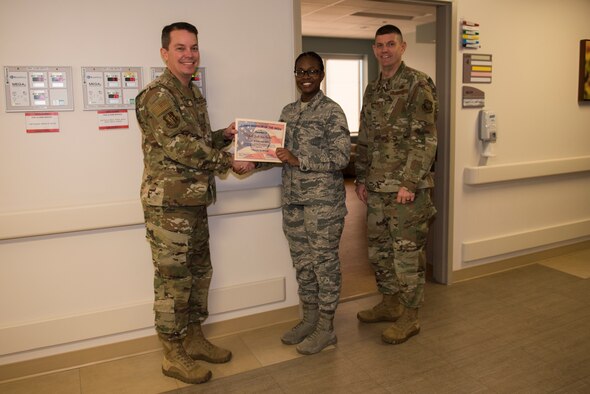 U.S. Air Force Col. Jeffrey Nelson, left, 60th Air Mobility Wing commander, and Command Chief Master Sgt. Derek Crowder, right, 60th AMW command chief, recognize Airman 1st Class Jodi-Ann Noyan, center, 60th Inpatient Operations Squadron aerospace medical technician, Feb. 4, 2020, at Travis Air Force Base, California. Noyan was the Warrior of the Week from Feb. 2 – 8. The program recognizes Airmen who have made significant contributions to their units. (U.S. Air Force photo by Airman 1st Class Cameron Otte)