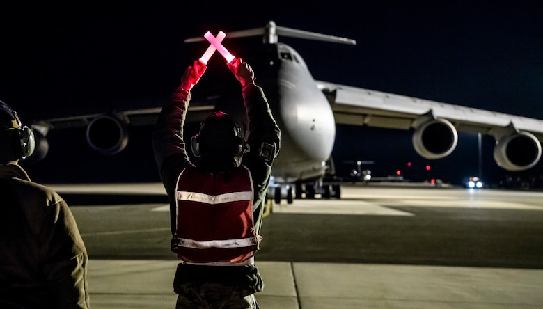 An aircraft maintainer from the 436th Aircraft Maintenance Squadron blocks in the C-5M Super Galaxy dubbed Reach 190 Jan. 28, 2020, on Dover Air Force Base, Del. The aircrew, consisting of 9th Airlift Squadron and 436th Aircraft Maintenance Squadron personnel, started on their mission Jan. 13, 2020, only to return to Dover 15 days later after encountering numerous challenges and an inflight medical emergency along the way. (U.S. Air Force photo by Senior Airman Christopher Quail)