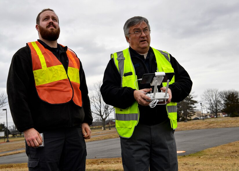 Photo of two individuals operating a drone.