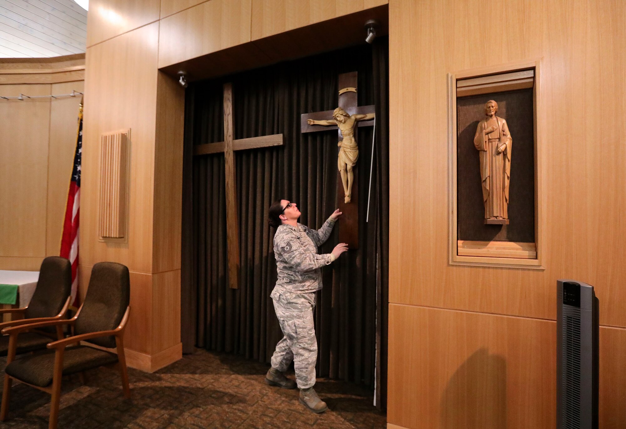 Tech. Sgt. Crystal McClellan, non-commissioned officer in charge of religious affairs, shows how a plain cross for Protestant services or the crucifix for Catholic services can be displayed in the sanctuary.