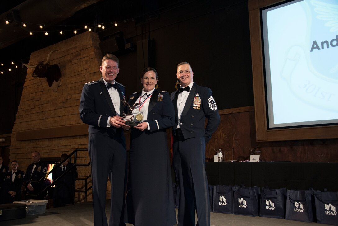 Colonel Mitch Hanson, 301st Fighter Wing commander and Chief Master Sgt. Rob Safley, 301st command chief hand winner Capt. Tiara Puro, 301 FW Force Support Squadron the Company Grade Officer of the Year award at the 301 FW Annual Awards Ceremony held on February 1 at River Ranch, Fort Worth, Texas. (U.S. photo by Tech. Sgt. Melissa Harvey)