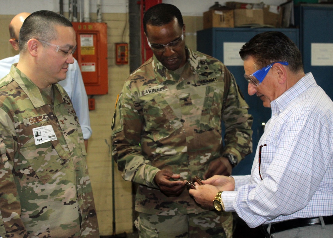 LA Troop Support Commander Army Brig. Gen. Gavin Lawrence, center, and Industrial Hardware Director Air Force Col. Adrian Crowley, left, listen as SPS Technologies Sales Manager Joseph DiGiacomo, right, explains the finishing process on a bolt during a tour of the Jenkintown, Pennsylvania facility Feb. 5, 2020.