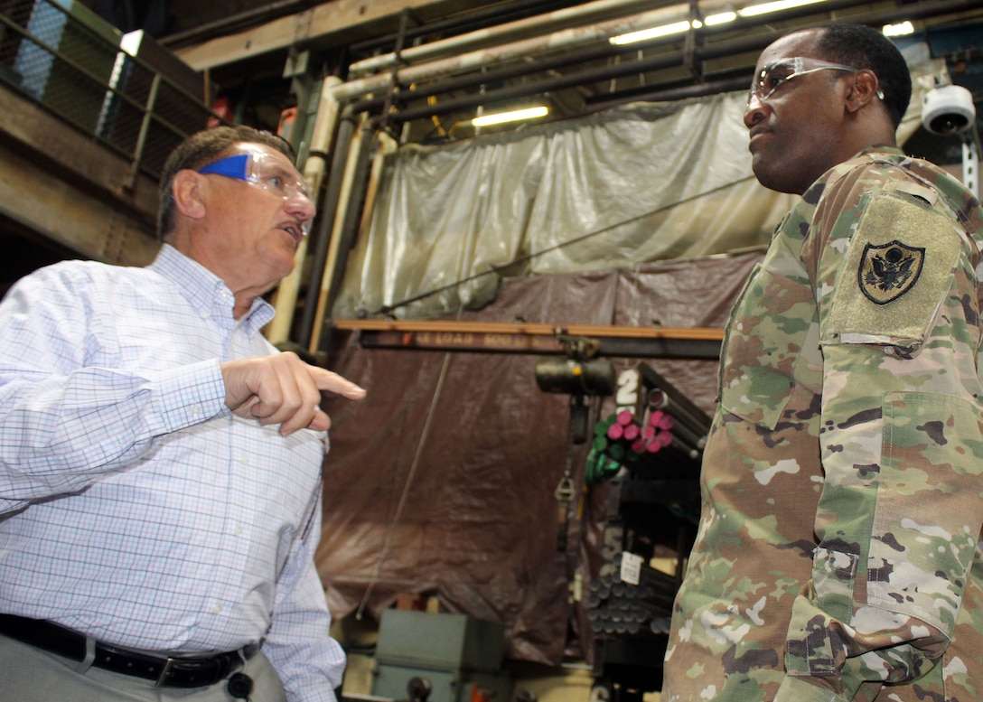 DLA Troop Support Commander Army Brig. Gen. Gavin Lawrence, right, listens as SPS Technologies Sales Manager Joseph DiGiacomo, left, explains how raw materials used in manufacturing are tracked all the way to the end product during a facility tour Feb. 5, 2020 in Jenkintown, Pennsylvania.