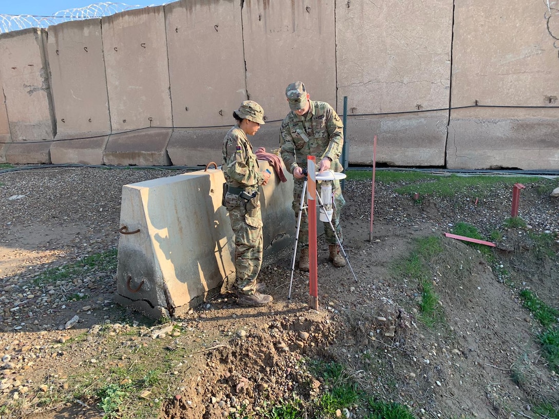 Sgt. Jonathan Skiles, 480th MED DET, partners with Staff Sgt. Helen Tokaiqali, UK J4 MED, and Spanish counterparts to set up a mosquito light trap on post in Iraq.