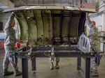 Sheet metal technicians with the Georgia Air National Guard's 116th Air Control Wing and the 461st Air Control Wing secure an engine aircraft cover on a cowling fixture table at Robins Air Force Base, Georgia, April 3, 2019.