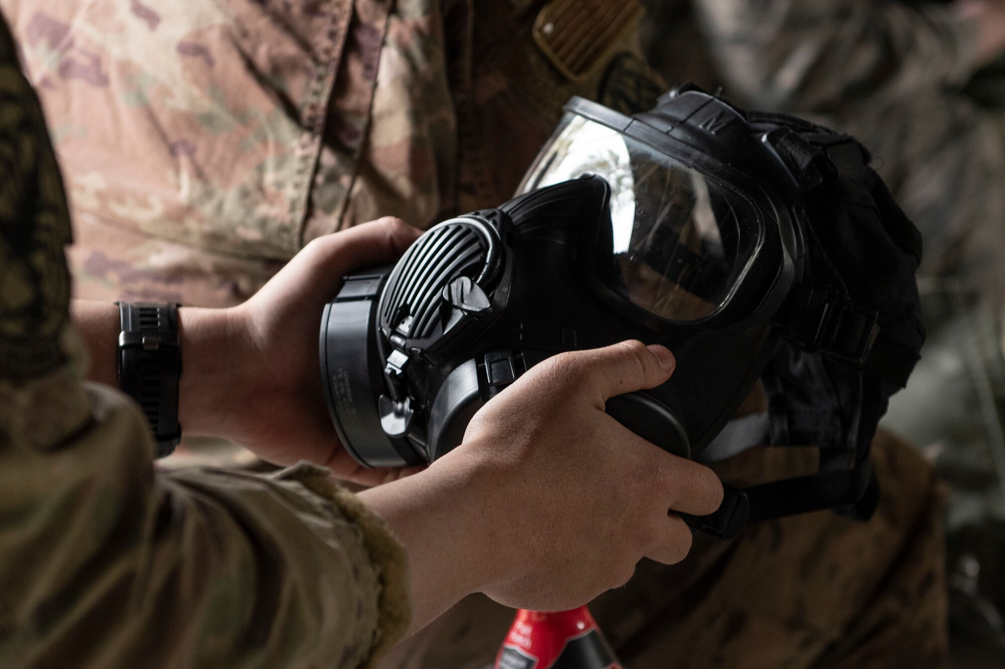 A photo of an Airman checking his gas mask during a chemical, biological, radiological, nuclear, and explosive defense training.