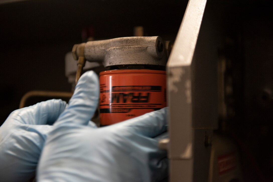 A photo of an Airman screwing on an oil can.