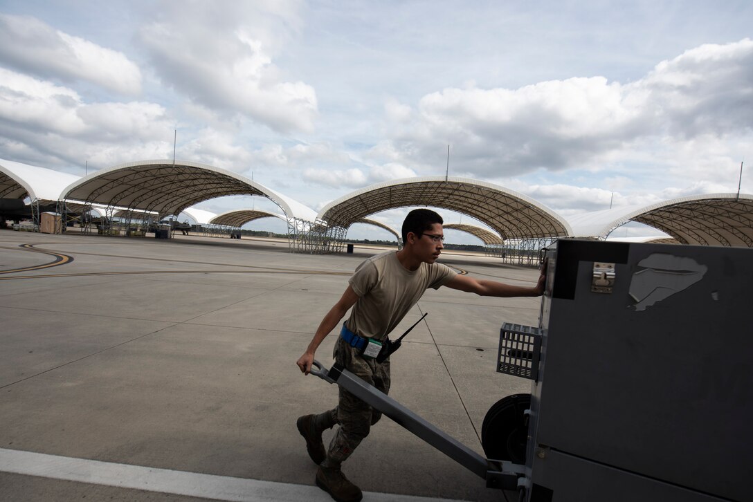 A photo of an Airman pushing a generator.