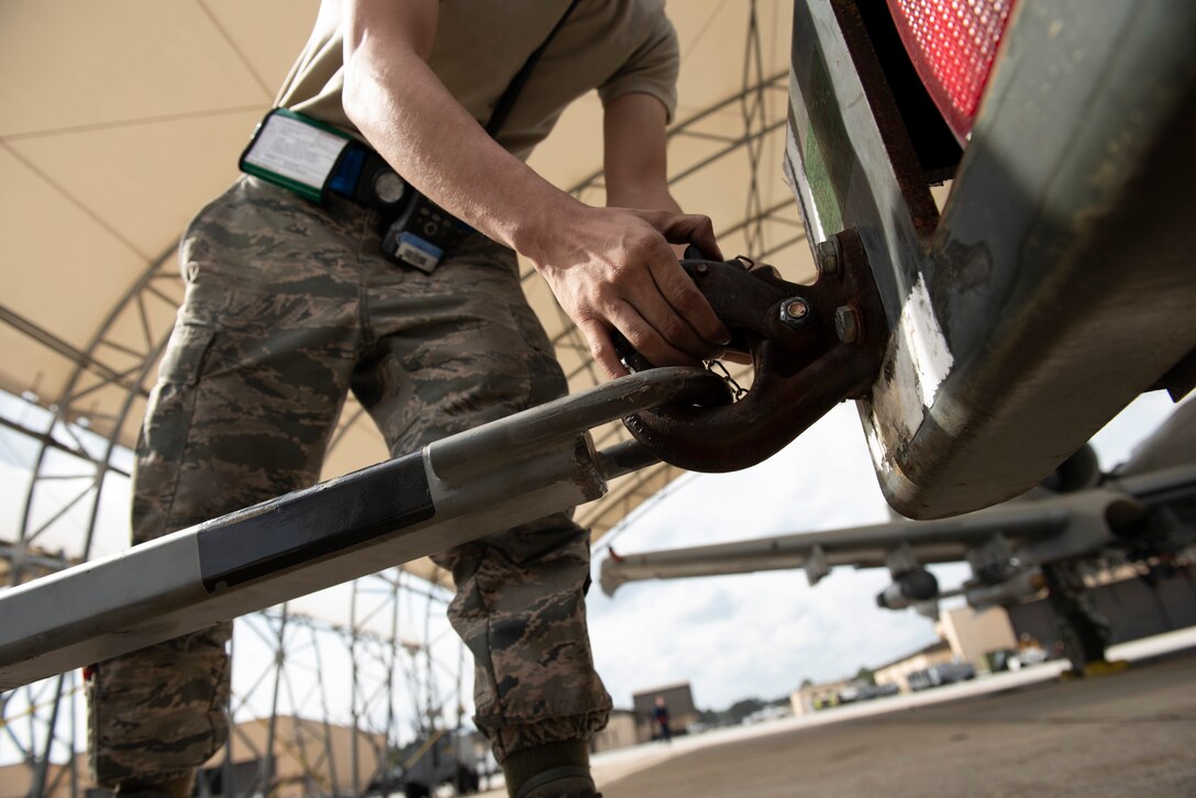 A photo of an Airman unhooking a generator from a truck