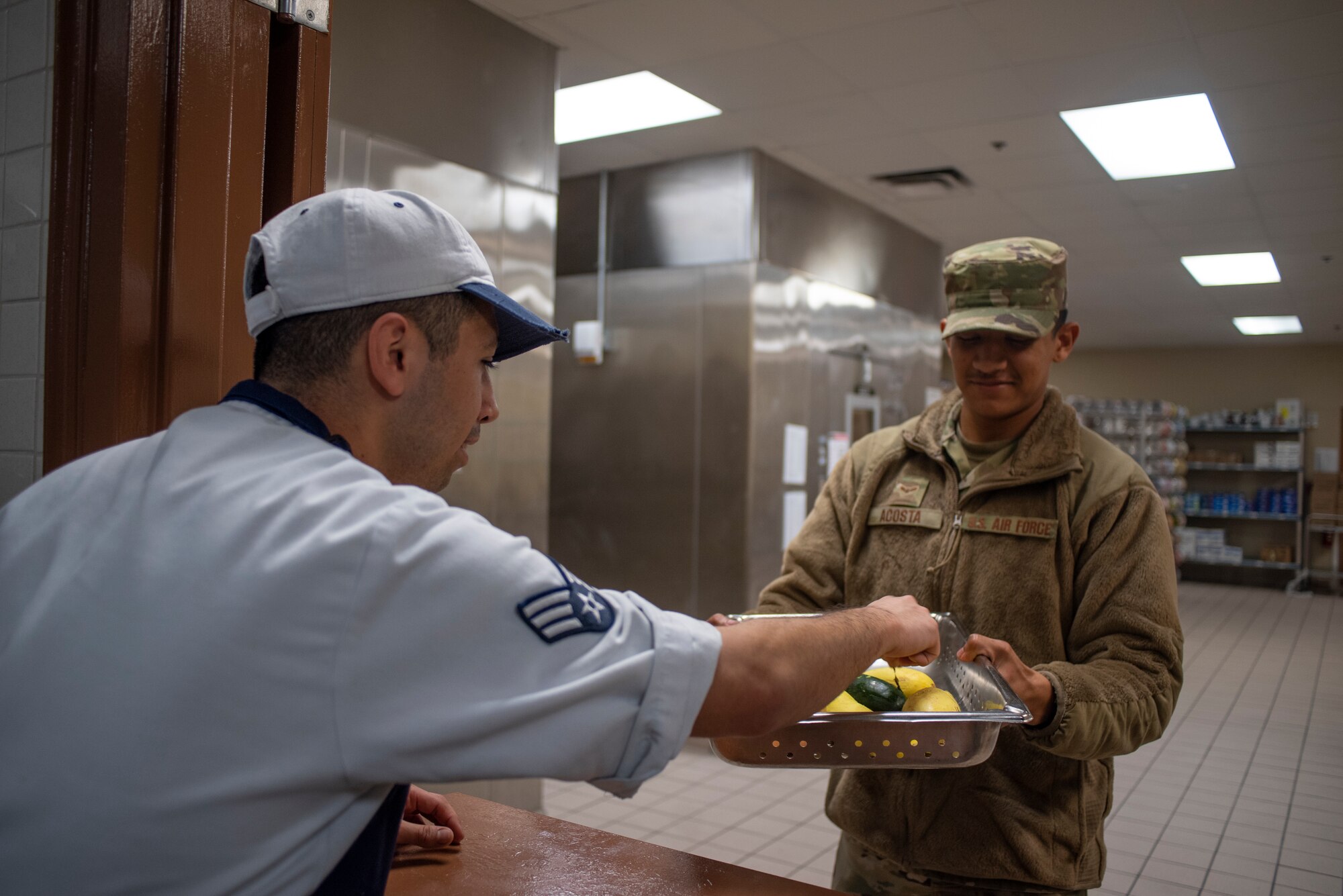 Airman 1st Class Joshua Acosta, (right) the store room clerk at the Diner’s Reef dining facility provides food to be used in a recipe at MacDill Air Force Base, Fla., Jan. 30, 2020.