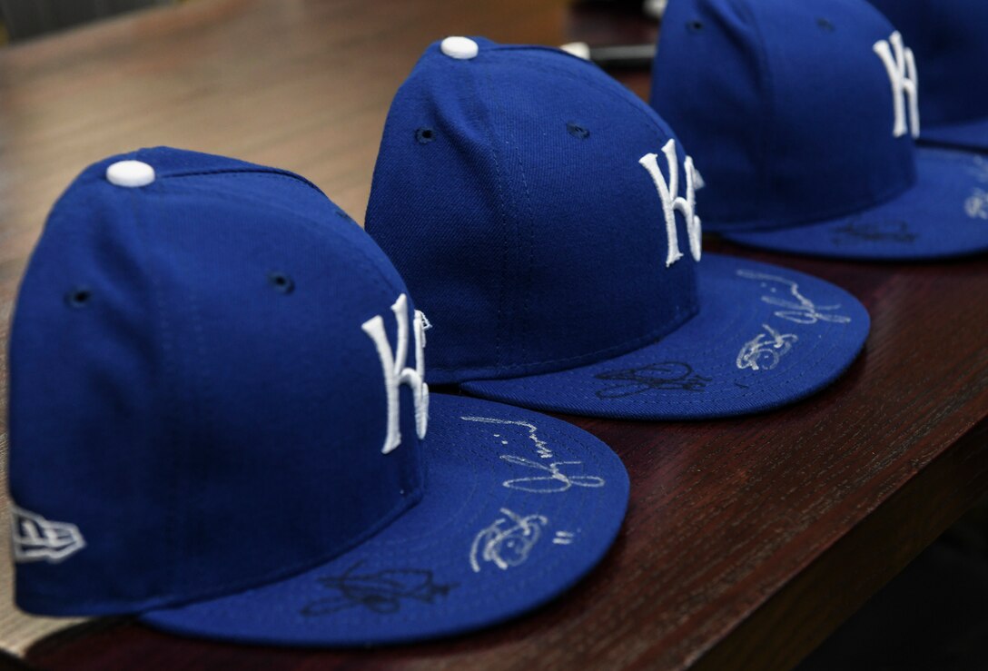 Kansas City Royals hats sit on a table during a meet and greet session at Whiteman Air Force Base, Mo., Jan. 30, 2020. During their visit, many Airmen brought baseball collectors’ items such as baseballs, cards and clothing, to be autographed by members of the baseball team. (U.S. Air Force photo by Staff Sgt. Sadie Colbert)