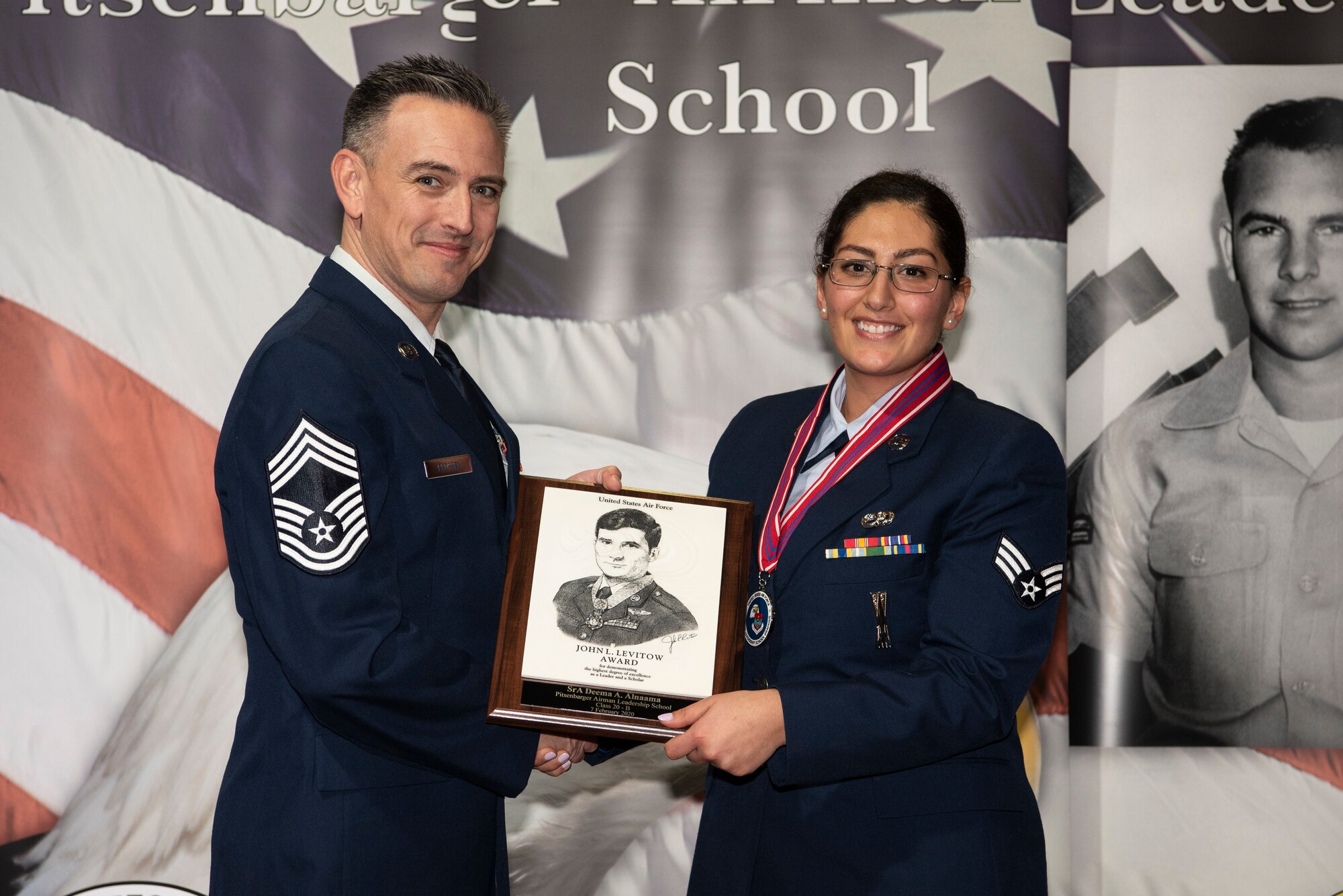 U.S. Air Force Chief Master Sgt. Jason Redfern, 52nd Logistics Readiness Squadron chief enlisted manager, left, presents the John L. Levitow award to Senior Airman Deema Alnaama, 52nd Aircraft Maintenance Squadron weapons load crew member, during the Pitsenbarger Airman Leadership School class 20-B graduation at Spangdahlem Air Base, Germany, Feb. 7, 2020. The award is given to the ALS graduate who demonstrates the most professional leadership and academic performance. (U.S. Air Force photo by Airman 1st Class Valerie Seelye)