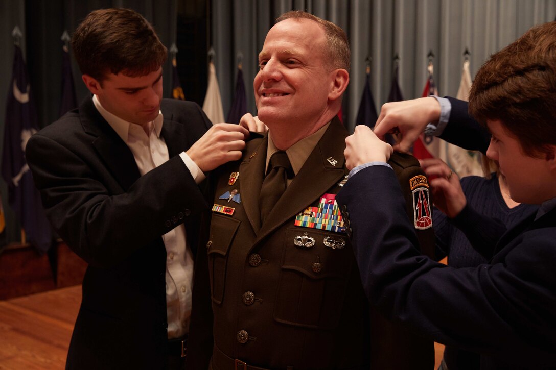 U.S. Army Reserve Maj. Gen. John Phillips smiles as his sons Ryan and Stone pin the two-star insignia to the shoulders of his Army Green Service Uniform during his promotion ceremony held in Alexander Hall, Fort Gordon, Ga. Feb. 9, 2020.