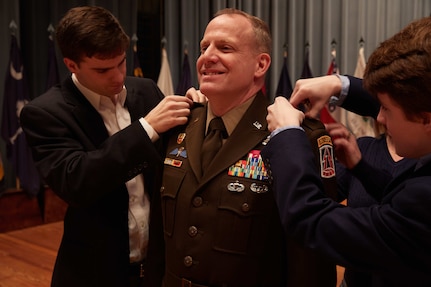 U.S. Army Reserve Maj. Gen. John Phillips smiles as his sons Ryan and Stone pin the two-star insignia to the shoulders of his Army Green Service Uniform during his promotion ceremony held in Alexander Hall, Fort Gordon, Ga. Feb. 9, 2020.