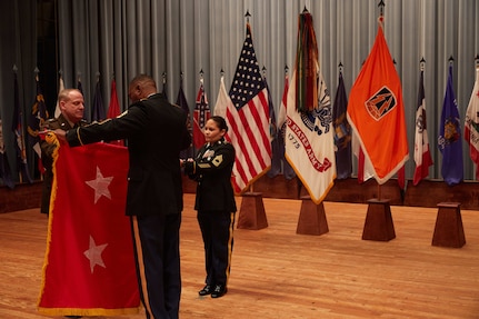 U.S. Army Reserve Maj. Gen. John Phillips (left) and Command Sgt. Maj. Edward Simpson unfurl his 2-star flag during his promotion ceremony held in Alexander Hall, Fort Gordon, Ga. Feb. 9, 2020.