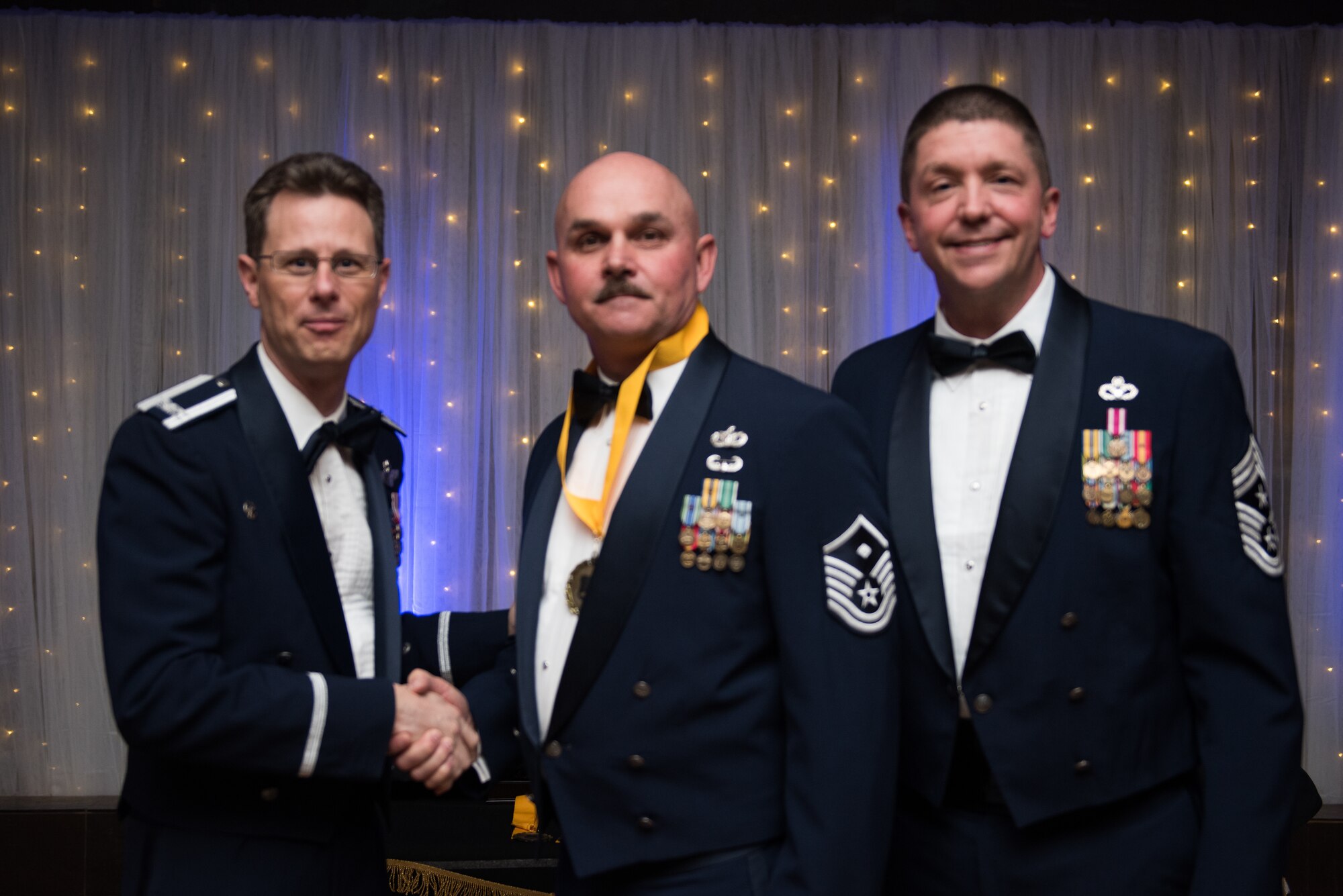 Col. Jeffrey Downs, 940th Air Refueling Wing commander, and Chief Master Sgt. David J. Melby, 940 ARW command chief, present an award to Master Sgt. Peter Thompson, 940th Mission Support Group first sergeant.