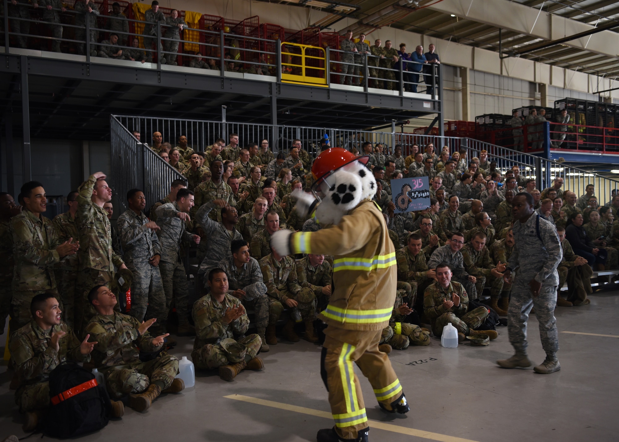 Sparky, National Fire Protection Association mascot, and U.S. Air Force Tech. Sgt. Derwin Finley, 312th Training Squadron military training leader, work together to amp up the attendees before the 17th Training Group Drill Competition inside the Louis F. Garland Department of Defense Fire Academy High Bay on Goodfellow Air Force Base, Texas, Feb. 7, 2020. Many agencies on base have mascots, which make appearances during special events to promote team unity and morale. (U.S. Air Force photo by Airman 1st Class Abbey Rieves)