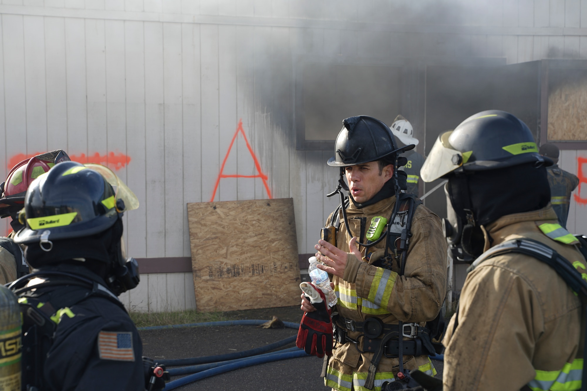 Arturo Perez, center, San Ramon Valley Fire Department instructor, instructs Airmen from the 60th Civil Engineer Squadron during a live burn training at Travis Air Force Base, California, Jan. 14, 2020. Travis Fire Emergency services and 10 other fire departments used four buildings at Travis AFB for live-fire training before conducting a final controlled burn to remove them. (Courtesy photo)