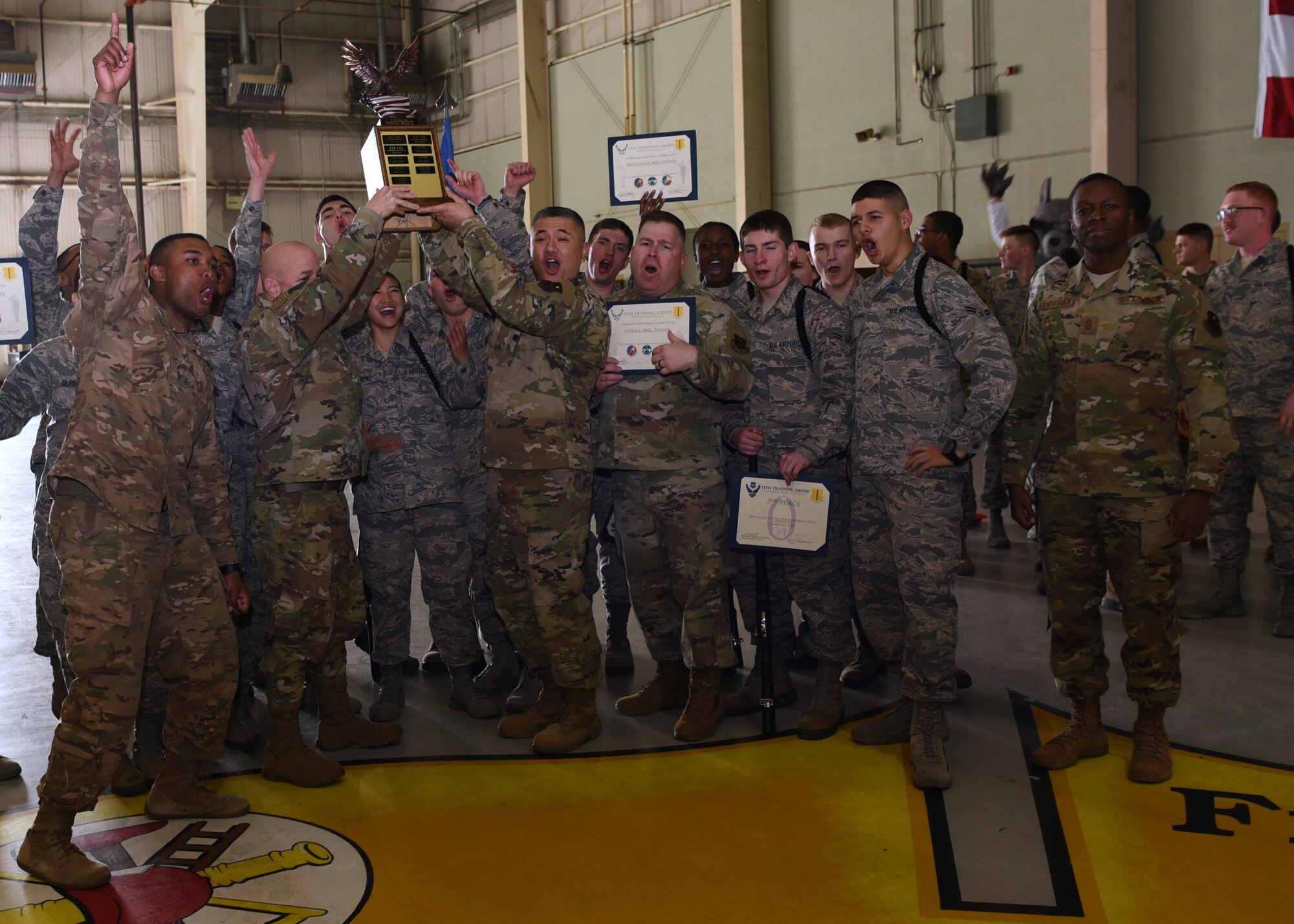 U.S. Air Force Airmen from the 315th Training Squadron, cheer as their team wins an award from the 17th Training Group Drill Competition inside the Louis F. Garland Department of Defense Fire Academy High Bay on Goodfellow Air Force Base, Texas, Feb. 7, 2020. Three training squadrons competed in four different drill categories in the quarterly event. (U.S. Air Force photo by Airman 1st Class Abbey Rieves)