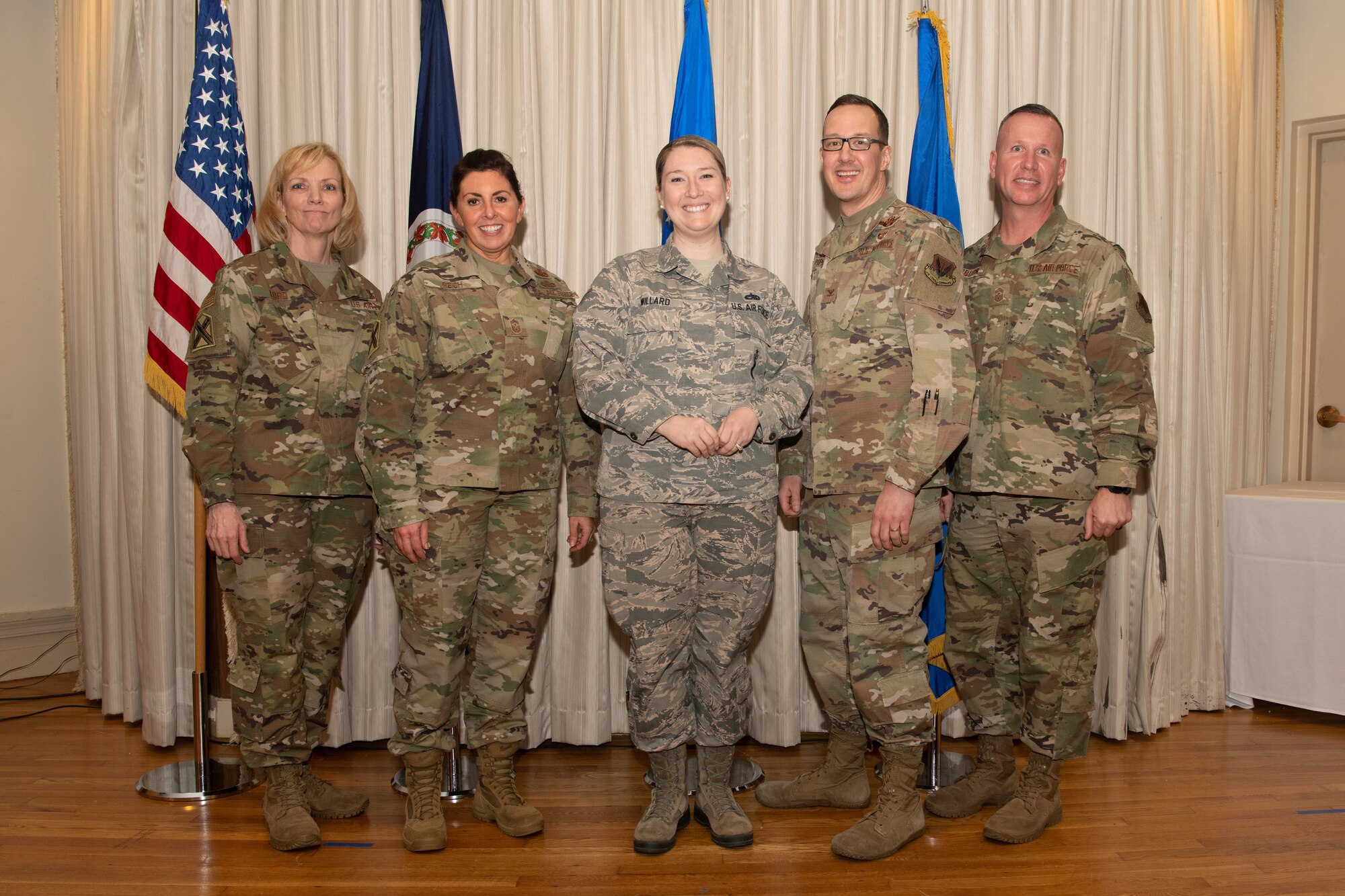 Airmen on a stage pose for a photo with award
