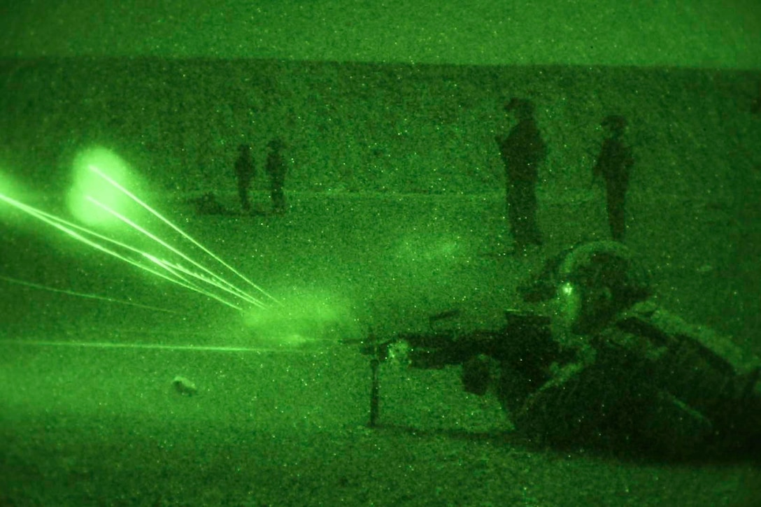 A soldier seen in a green light fires a weapon.