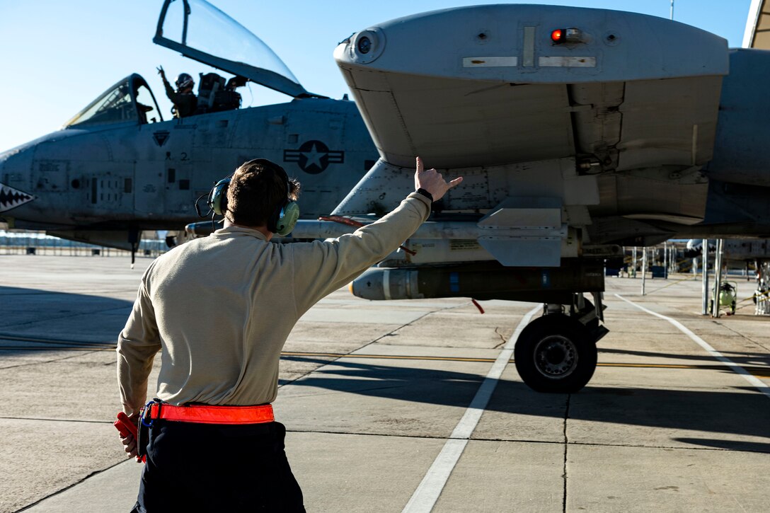 Photo of an Airman signaling to a pilot.