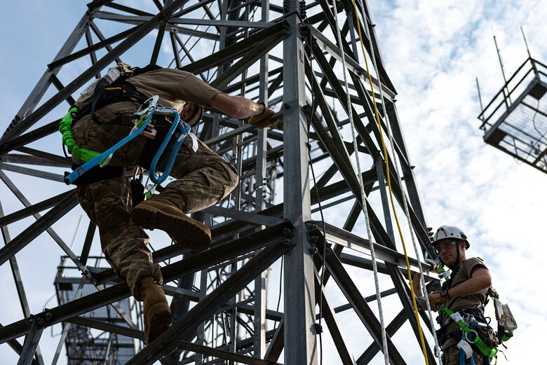 Photo of Airmen climbing a radio antenna tower.