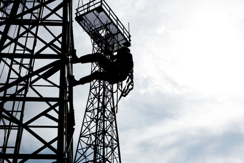 Photo of a commander rappelling down a radio antenna tower.