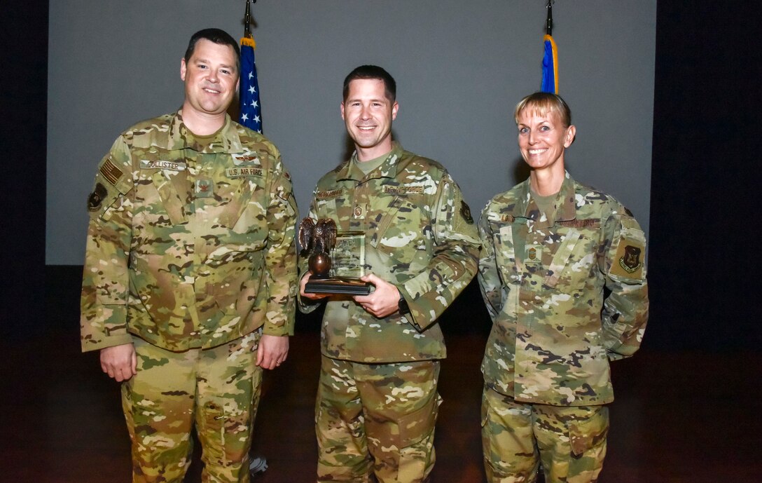 The newly promoted Master Sgt. David Underwood (center), 913th Operations Support Squadron, was selected at the group's non commissioned officer of the 2019 annual award period. Col. Dan Collister (left), 913th Airlift Group deputy commander, and Chief Master Sgt. Kimberly Lord, 913th Airlift Group superintendent, hosted an all call to honor the 2019 award winners on Feb. 8, 2020, at Little Rock Air Force Base, Ark. (U.S. Air Force Reserve photo by Senior Airman Nathan Byrnes)