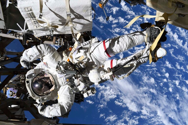 An astronaut flexes his muscles in his spacesuit while posing for a photo in space.