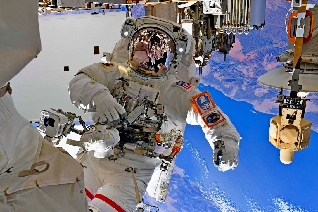 An astronaut is photographed in space, the earth visible below him.