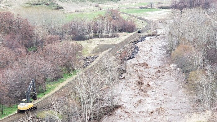 An excavator driving towards eroding section of road in Milton Freewater, Feb. 7.