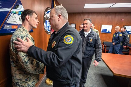 Hospital Corpsman 3rd Class Christopher S. Painter is embraced by District Fire Chief Jack D. Woodard following presentation of the Navy and Marine Corps Achievement Medal to Painter Feb. 11. Painter rendered life-saving aid to Woodard's son, Garrett, an employee at Puget Sound Naval Shipyard & Intermediate Maintenance facility.