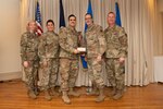 Airmen on a stage pose for a photo with award