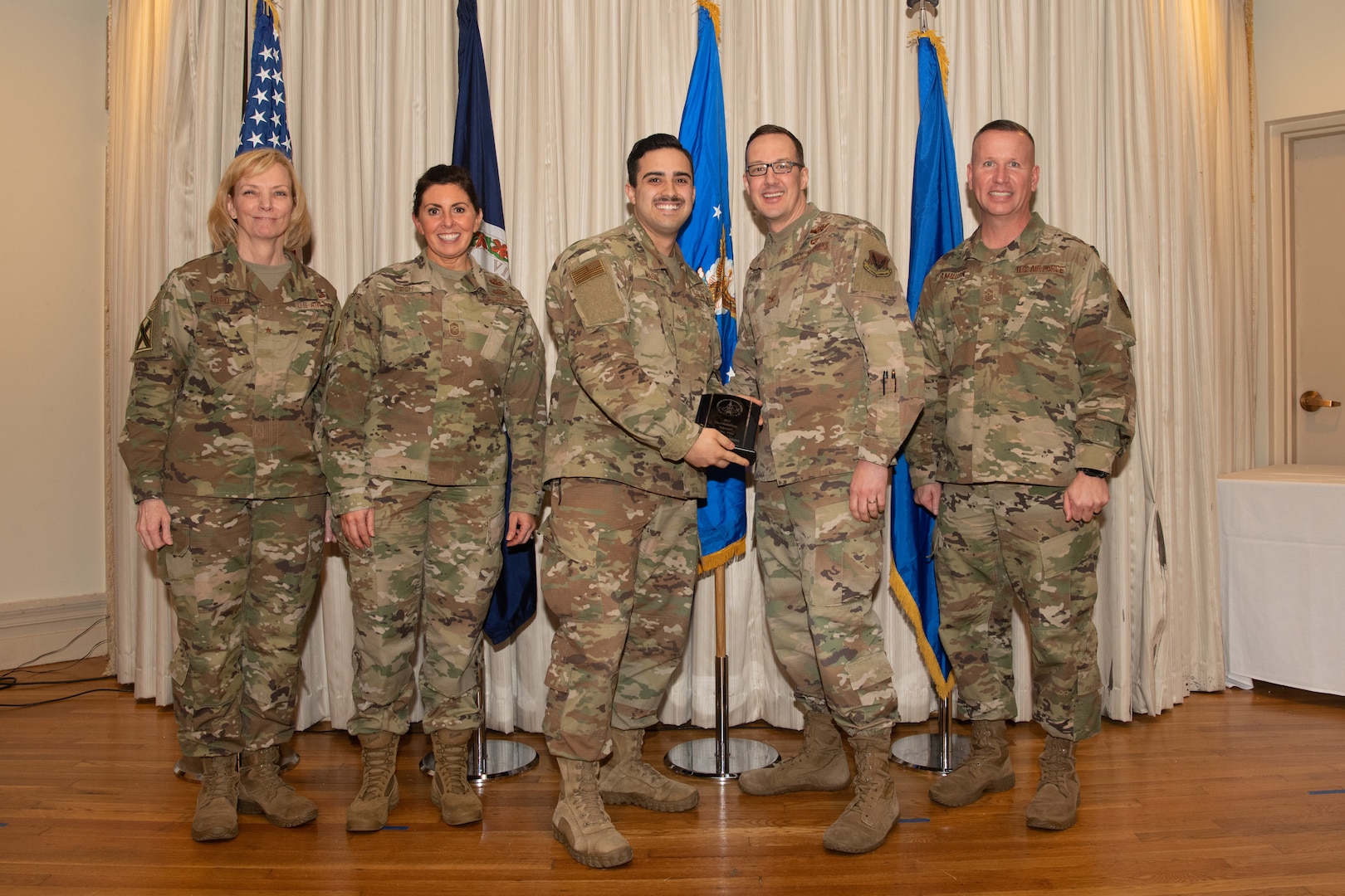 Airmen on a stage pose for a photo with award