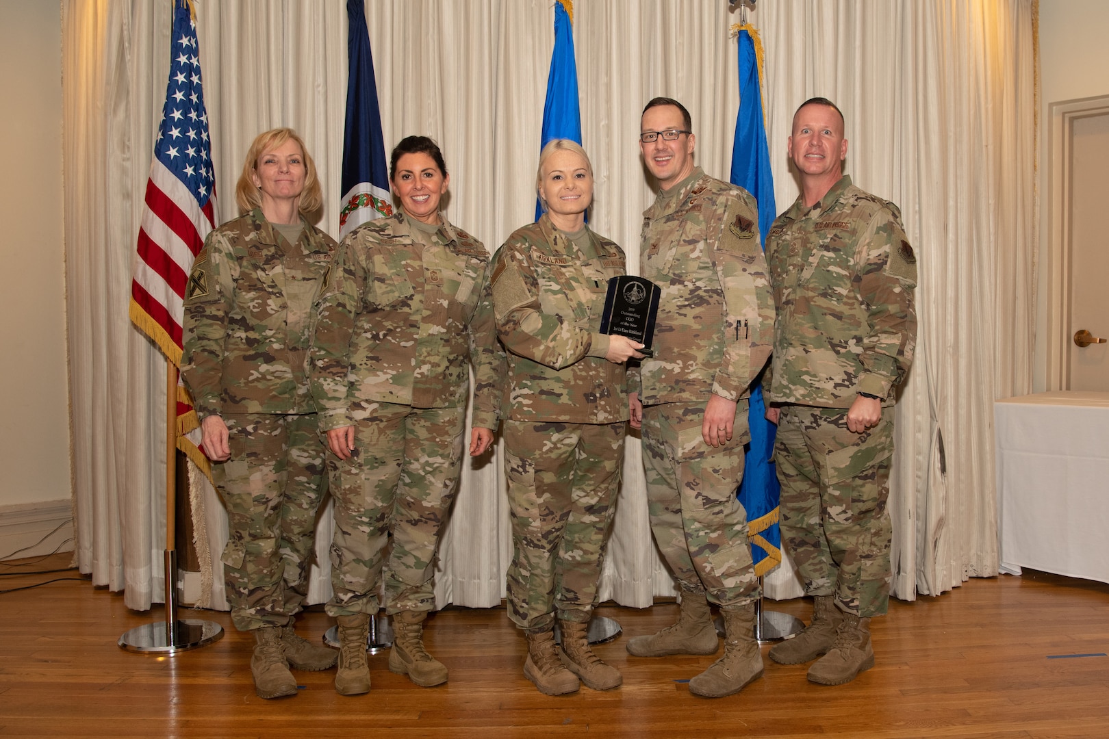 Airmen on a stage pose for a photo with award