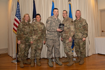 Airmen on a stage pose for a photo with award