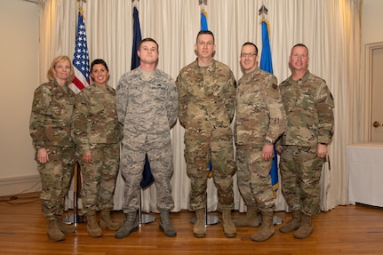 Airmen on a stage pose for a photo with award