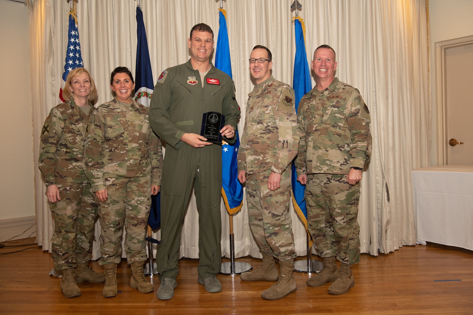 Airmen on a stage pose for a photo with award