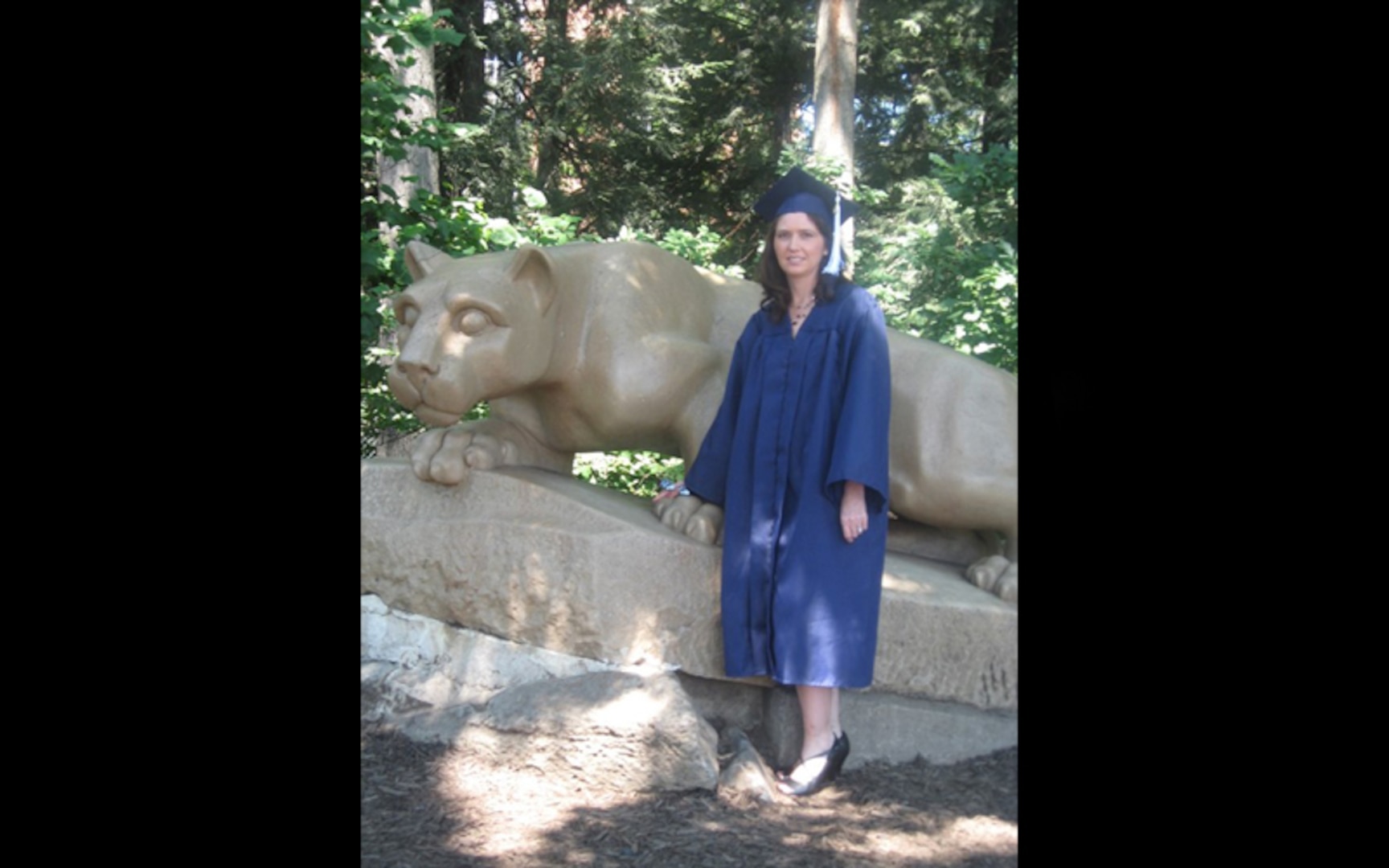 A woman wears her blue graduation cap and gown