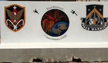 Sgt. 1st Class Damien Cavazos, detachment sergeant, Detachment B, 1st Space Company, Qatar, paints the unit’s retainer wall with the unit, battalion and brigade logos as a morale booster for his fellow Soldiers. The detachment belongs to the 1st Space Battalion, 1st Space Brigade, U.S. Army Space and Missile Defense Command. (Courtesy photo)