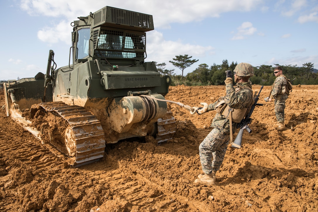 U.S. Marines utilize hand and arm signals to communicate via over heavy machinery noise at Engineer Training Area, Camp Hansen, Okinawa, Japan, Feb. 6.