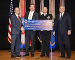 Four men hold a ceremonial check presented to DLA for meeting its monetary goal during the CFC awards ceremony Feb. 11.