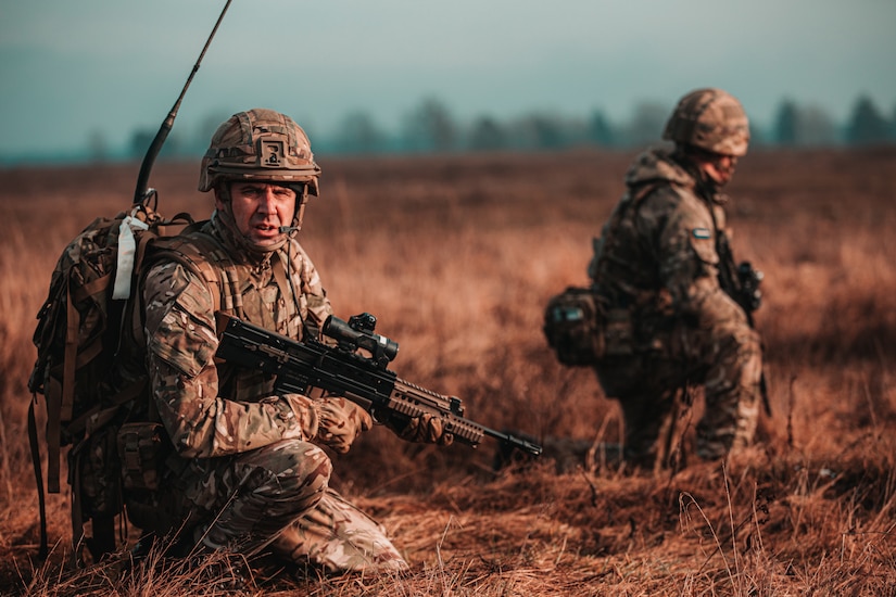 Soldiers with guns participate in a field exercise