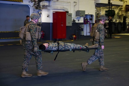 Marines with the 31st Marine Expeditionary Unit (MEU) and Sailors with the amphibious assault ship USS America (LHA 6) transport a casualty from a simulated combat zone in order to further assess his wounds during a Tactical Combat Casualty Care (TCCC) exercise