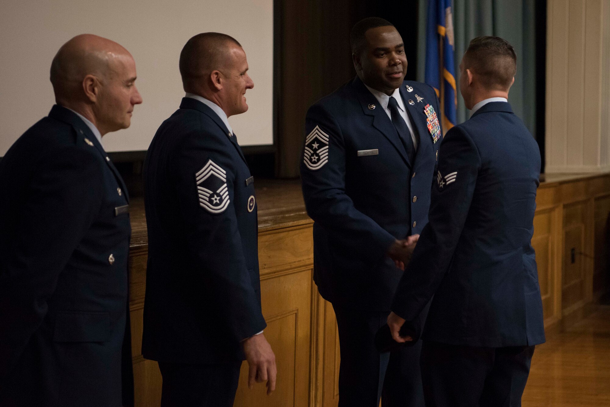 The graduation official party, including Chief Master Sgt. Robert L. Zackery III, 47th Flying Training Wing command chief master sergeant, congratulate a Tactical Air Control Party (TACP) Apprentice Course graduate at Joint Base San Antonio-Lackland, Texas, Dec. 13, 2019. Graduates were finally able to receive their black berets and blouse their dress blues after crossing the stage. (U.S. Air Force photo by Senior Airman Marco A. Gomez)